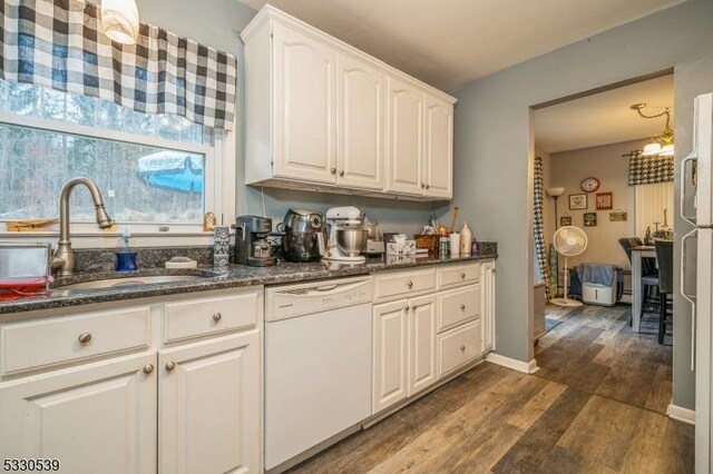 kitchen featuring dark stone counters, white dishwasher, white cabinets, sink, and dark hardwood / wood-style flooring