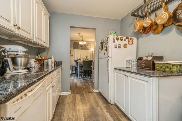 kitchen with dark stone countertops, light hardwood / wood-style flooring, white cabinets, and white appliances