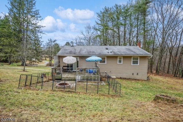 back of property featuring a lawn, an outdoor fire pit, and a wooden deck