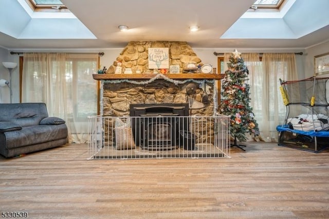 interior space featuring a skylight, a stone fireplace, and wood-type flooring