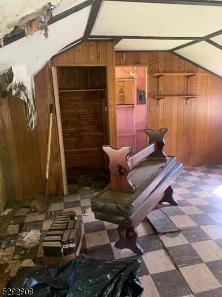 misc room featuring wood walls and lofted ceiling