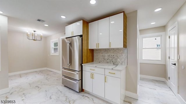 kitchen with light stone countertops, backsplash, high quality fridge, pendant lighting, and white cabinets