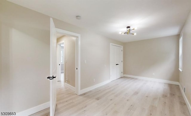 spare room with light wood-type flooring and an inviting chandelier