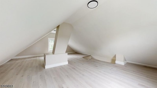 additional living space featuring lofted ceiling and light wood-type flooring