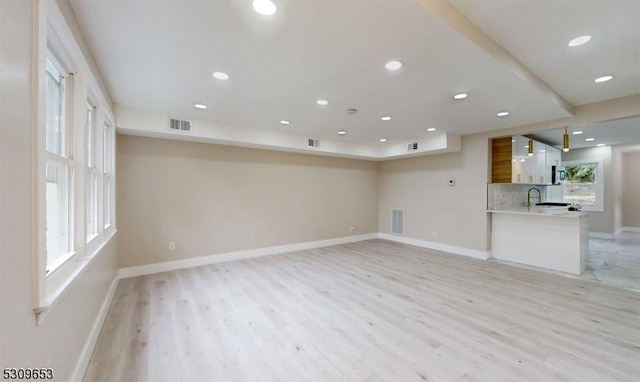 unfurnished living room with light hardwood / wood-style flooring and sink