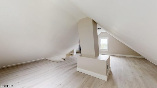 bonus room with light wood-type flooring and lofted ceiling