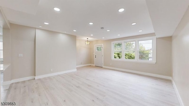 unfurnished room with light hardwood / wood-style floors and an inviting chandelier