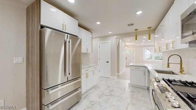 kitchen with sink, stainless steel appliances, backsplash, pendant lighting, and white cabinets