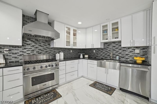 kitchen with a sink, stainless steel appliances, white cabinetry, wall chimney range hood, and marble finish floor