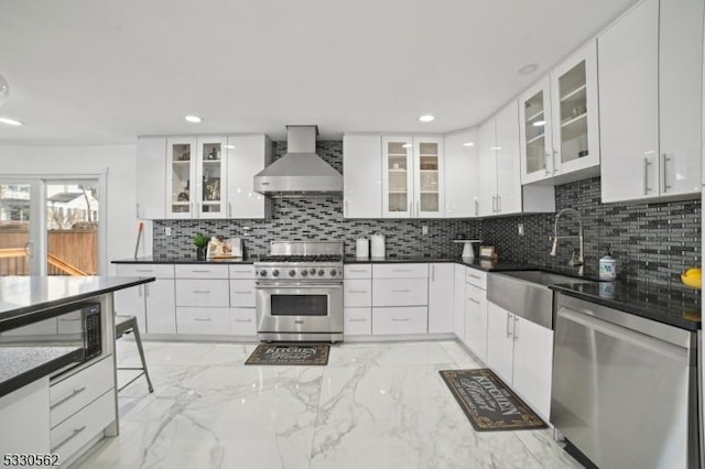 kitchen with marble finish floor, stainless steel appliances, wall chimney range hood, and a sink