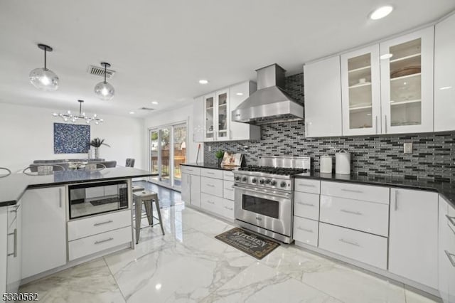 kitchen with dark countertops, white cabinetry, stainless steel stove, wall chimney exhaust hood, and built in microwave