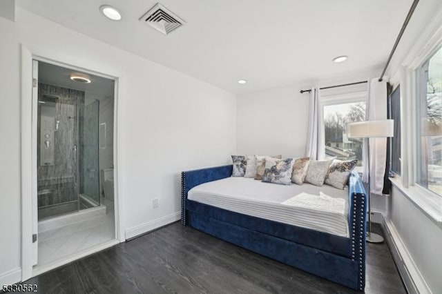 bedroom with wood finished floors, visible vents, baseboards, a baseboard heating unit, and connected bathroom