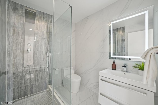 bathroom with vanity, a shower stall, toilet, and tile walls