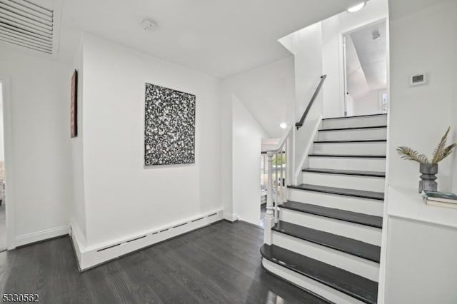 stairs with wood finished floors, baseboards, and a baseboard radiator