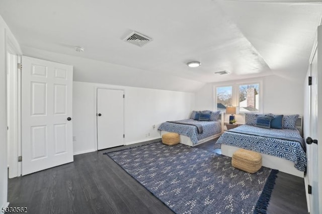 bedroom featuring dark wood-style floors, visible vents, and vaulted ceiling