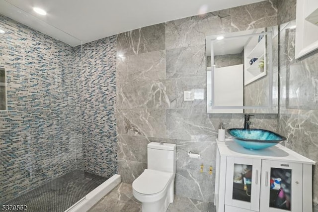 full bath featuring vanity, tile walls, toilet, and tiled shower