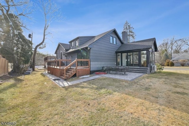 rear view of property featuring a patio area, a yard, a deck, and a sunroom