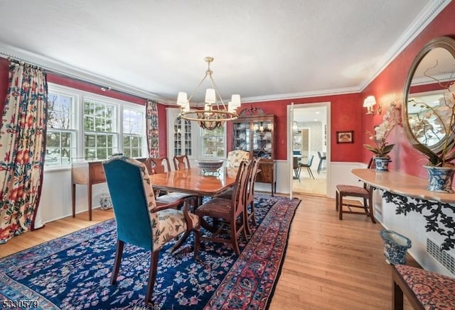 dining area with crown molding, light hardwood / wood-style floors, and a notable chandelier