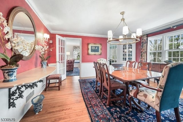 dining area with ornamental molding, a chandelier, and light hardwood / wood-style flooring