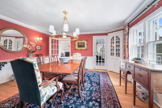 dining space featuring a notable chandelier, crown molding, and light wood-type flooring