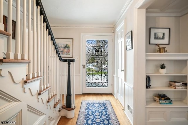 entryway featuring ornamental molding and light hardwood / wood-style floors