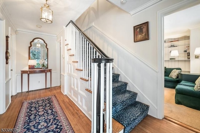 stairway with wood-type flooring and crown molding