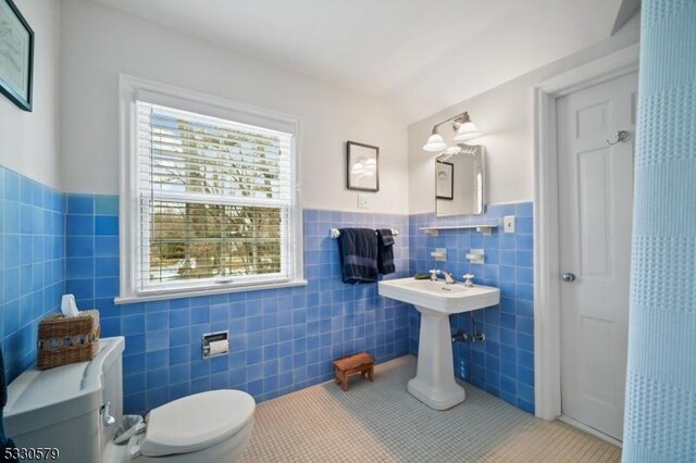 bathroom with tile patterned flooring, tile walls, and toilet