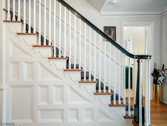 staircase featuring crown molding and hardwood / wood-style floors