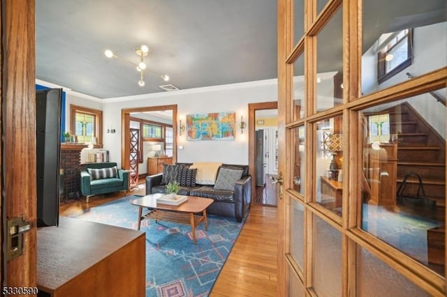 living area with stairs, visible vents, wood finished floors, and crown molding