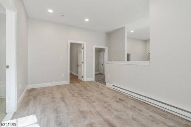 empty room featuring baseboard heating and light hardwood / wood-style flooring