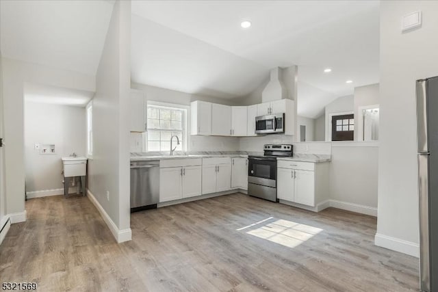 kitchen featuring decorative backsplash, stainless steel appliances, white cabinets, light hardwood / wood-style floors, and lofted ceiling