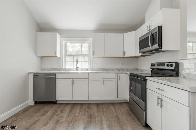 kitchen featuring light stone countertops, stainless steel appliances, white cabinetry, and sink