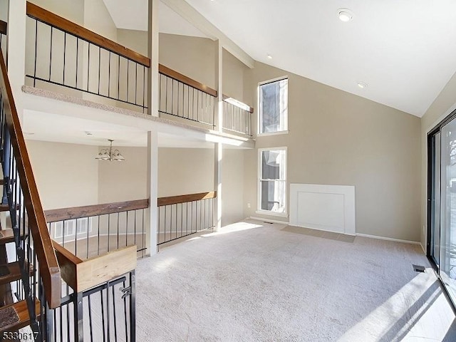 unfurnished living room with a chandelier, beam ceiling, carpet flooring, and high vaulted ceiling