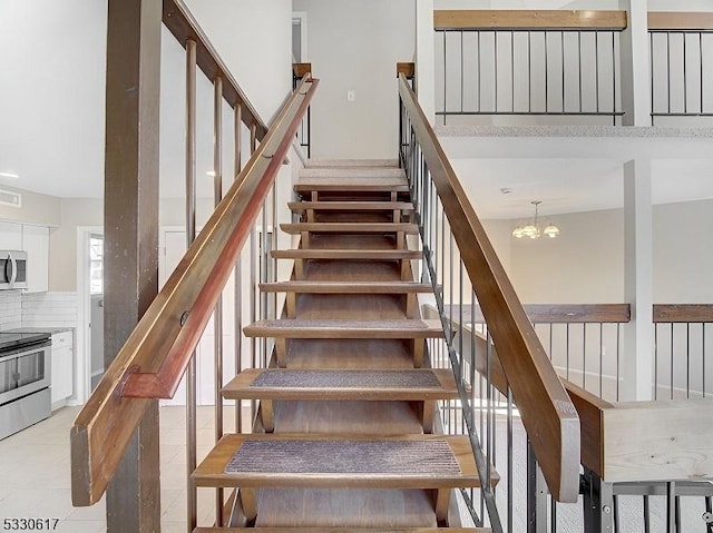 stairs with tile patterned floors and an inviting chandelier