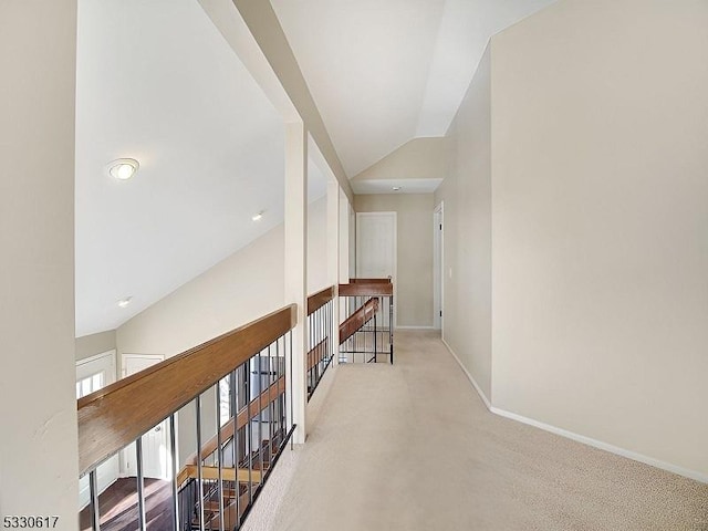 hallway with light colored carpet and vaulted ceiling