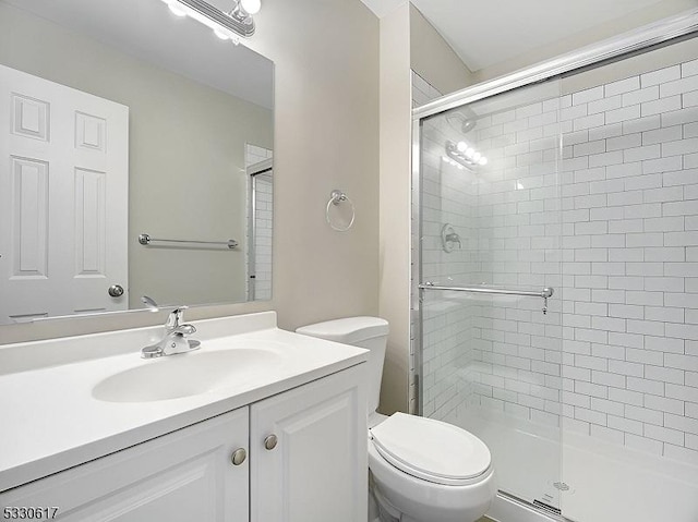 bathroom with vanity, toilet, and a shower with door