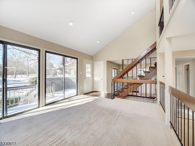 empty room featuring light colored carpet and high vaulted ceiling