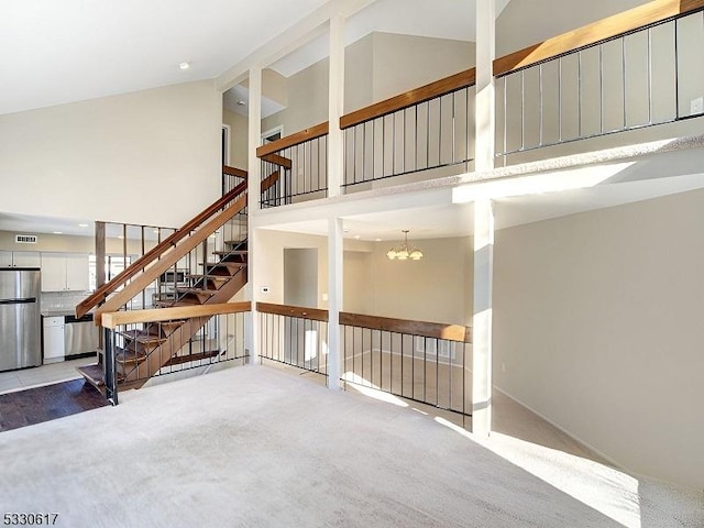 unfurnished living room with carpet floors, an inviting chandelier, and high vaulted ceiling