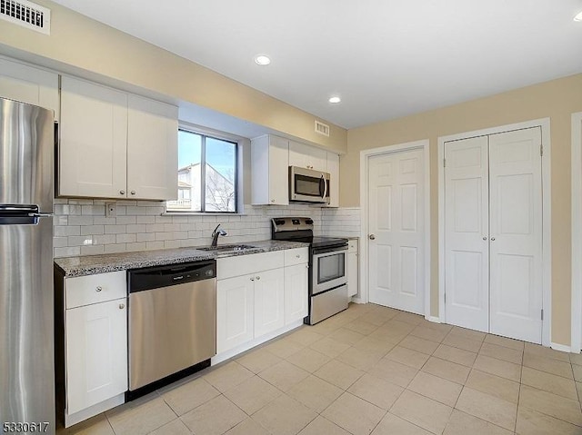 kitchen with stone counters, white cabinets, and stainless steel appliances