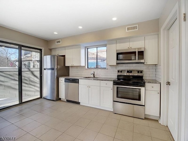 kitchen with white cabinets, stone countertops, sink, and appliances with stainless steel finishes