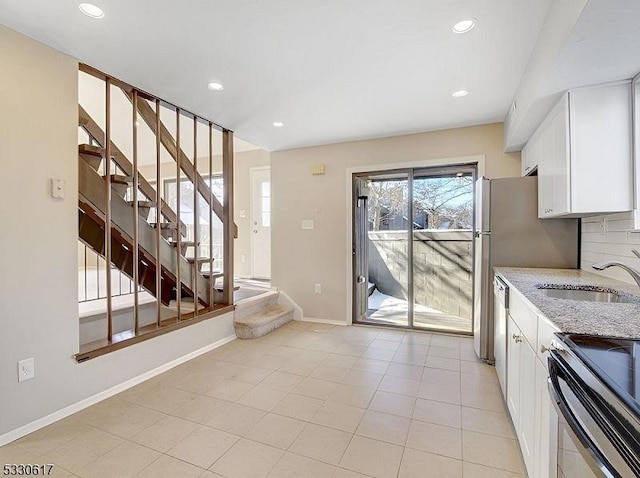 kitchen featuring white cabinets, sink, electric range, light stone countertops, and light tile patterned floors