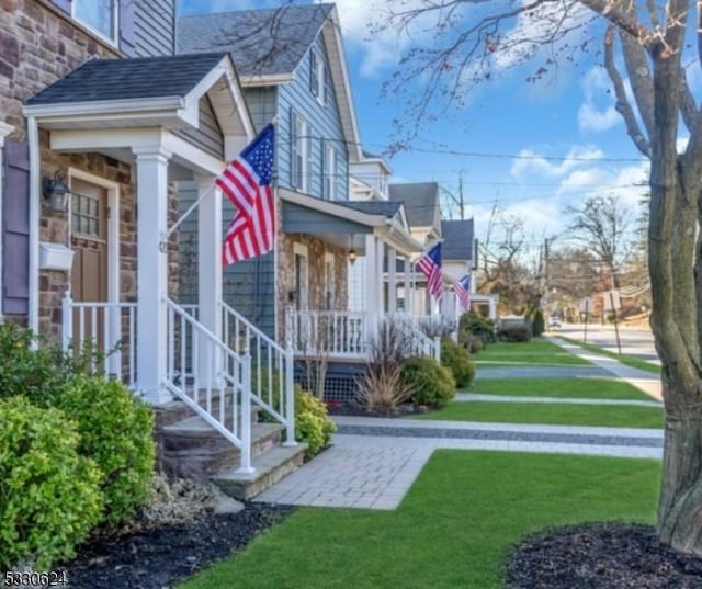 view of side of property featuring covered porch and a yard