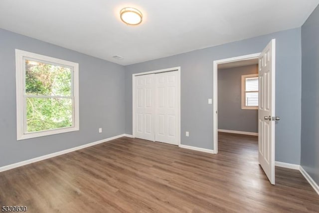 unfurnished bedroom featuring dark hardwood / wood-style flooring and a closet