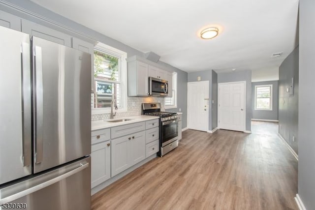 kitchen featuring white cabinets, sink, decorative backsplash, light wood-type flooring, and stainless steel appliances