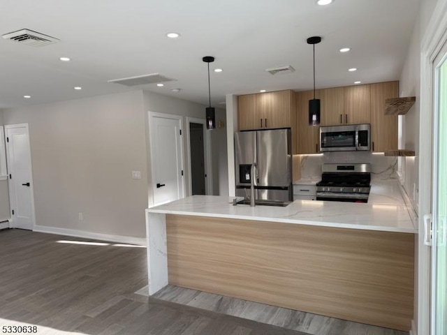 kitchen featuring kitchen peninsula, appliances with stainless steel finishes, dark hardwood / wood-style flooring, and hanging light fixtures