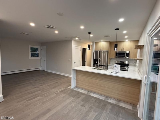 kitchen with light brown cabinets, a baseboard heating unit, hardwood / wood-style flooring, decorative light fixtures, and stainless steel appliances