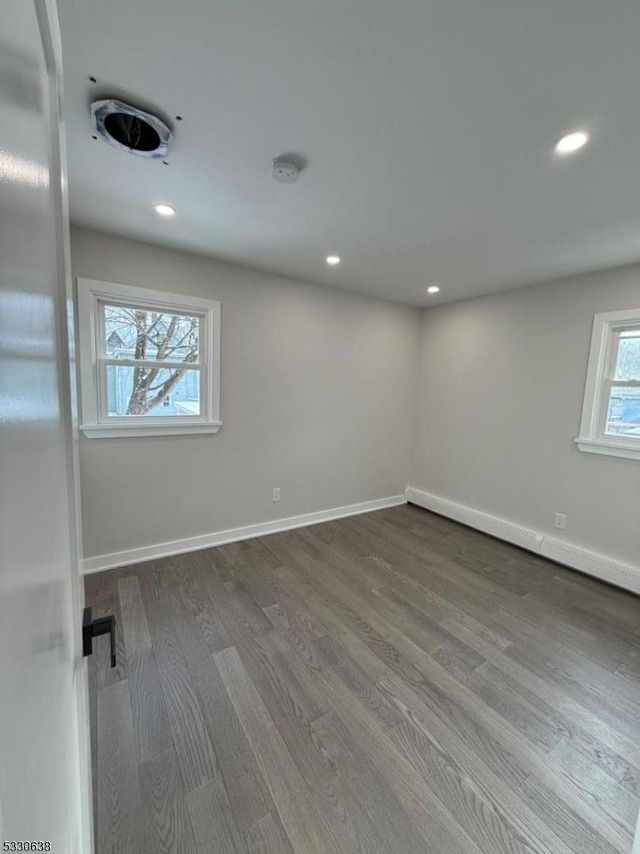 unfurnished room featuring hardwood / wood-style floors and a baseboard heating unit