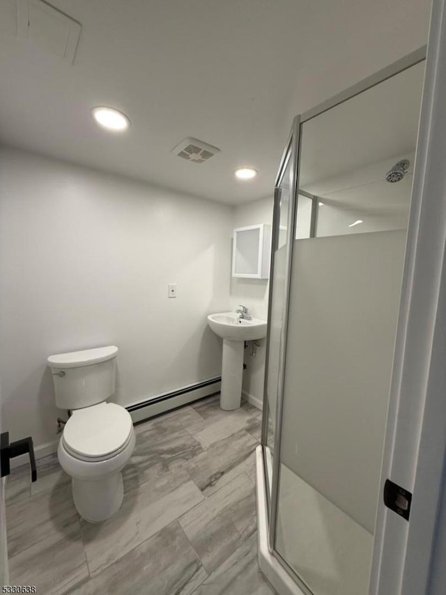 bathroom with baseboard heating, a shower with shower door, and toilet