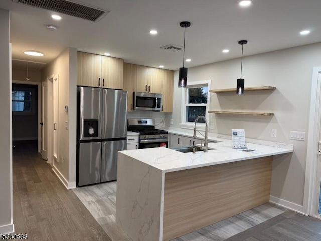 kitchen featuring pendant lighting, sink, appliances with stainless steel finishes, light stone counters, and kitchen peninsula