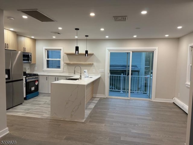 kitchen with kitchen peninsula, appliances with stainless steel finishes, a baseboard heating unit, sink, and pendant lighting